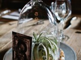 a creative wedding centerpiece of a metal plate, colorful buttons, an air plant or a succulent, a cloche and a table number