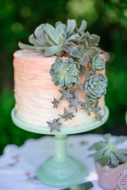a peachy pink ombre wedding cake topped and decorated with various succulents of various sizes is a fresh and pretty idea with a touch of color