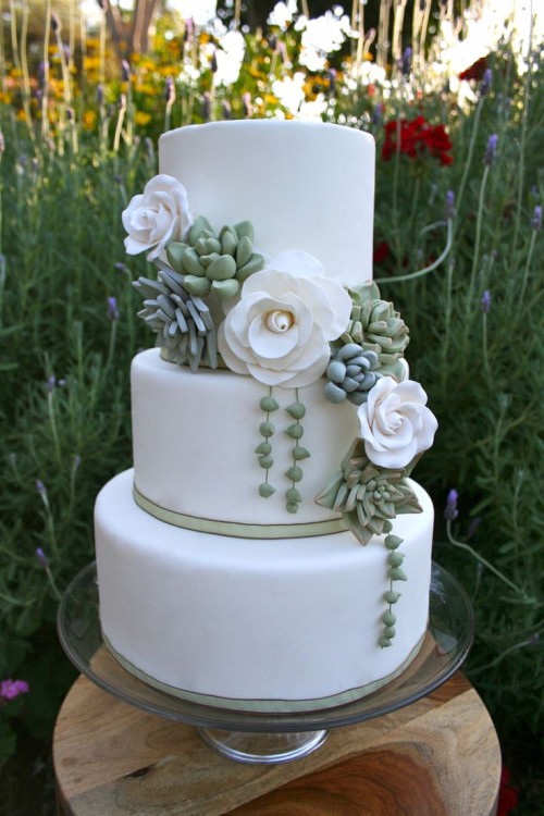 a sleek white buttercream wedding cake decorated with white sugar blooms and fresh succulents is a cool and stylish idea that will fit many wedding styles