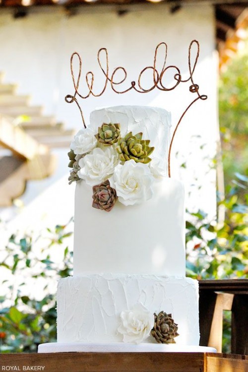 a white sleek and textural buttercream wedding cake decorated with white blooms and succulents, with a twine calligraphy topper is a stylish and pretty idea to rock