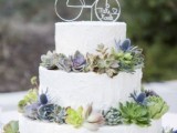 a white textural buttercream wedding cake decorated with various succulents and blue thistle, with a wire bike cake topper, is a fun and cool idea to rock at a bike-lover wedding