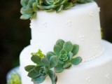 a white buttercream polka dot wedding cake decorated with succulents and topped with them for a stylish modern wedding done in neutrals