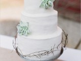 a white buttercream wedding cake decorated with twigs and sugar succulents is a cool solution for a modern rustic or other wedding