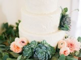 a white textural buttercream wedding cake decorated with pink blooms and succulents, with a greenery wreath is a stylish idea for a modern rustic wedding