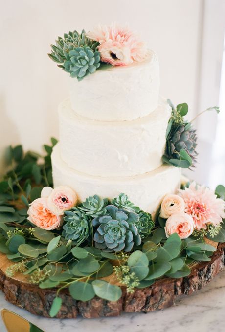 a white textural buttercream wedding cake decorated with pink blooms and succulents, with a greenery wreath is a stylish idea for a modern rustic wedding