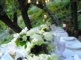 a neutral summer wedding tablescape with lush florals, greenery and a touch of dark and white place settings
