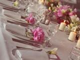 a neutral summer wedding table with white and pink florals and greenery, candles and neutral linens