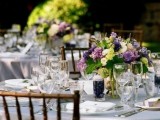 a neutral wedding table with purple and green blooms and candles looks chic and stylish