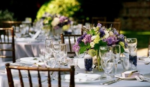 a neutral wedding table with purple and green blooms and candles looks chic and stylish
