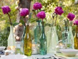a summer wedding tablescape with pastel linens, super bright blooms in bottles and candles looks relaxed and chic