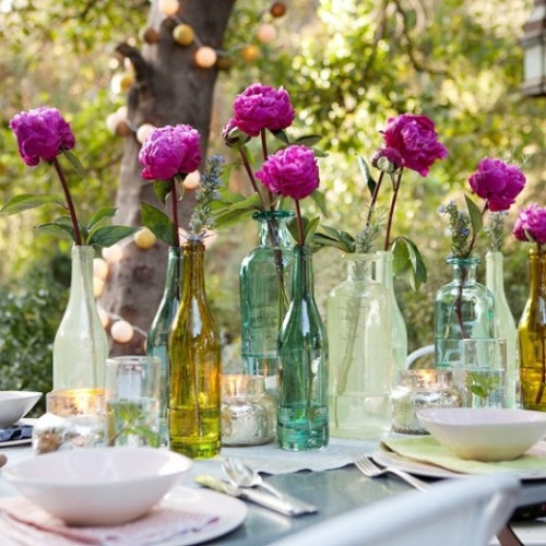 a summer wedding tablescape with pastel linens, super bright blooms in bottles and candles looks relaxed and chic
