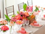 a colorful and refreshing summer wedding table with bright florals, greenery and some fruit plus colorful napkins and favor boxes