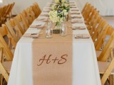 a chic neutral summer wedding tablescape with a burlap table runner, neutral blooms and wood slice holders plus candles