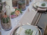 a chic neutral wedding tablescape with layered table runners, succulents in pots, candles and simple plates