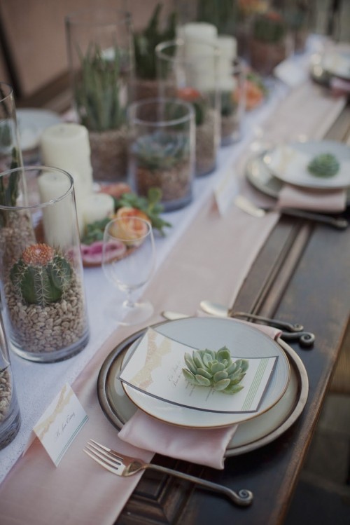 a chic neutral wedding tablescape with layered table runners, succulents in pots, candles and simple plates
