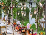 a super bright summer wedding tablescape with colorful blooms, greenery and candles over the table