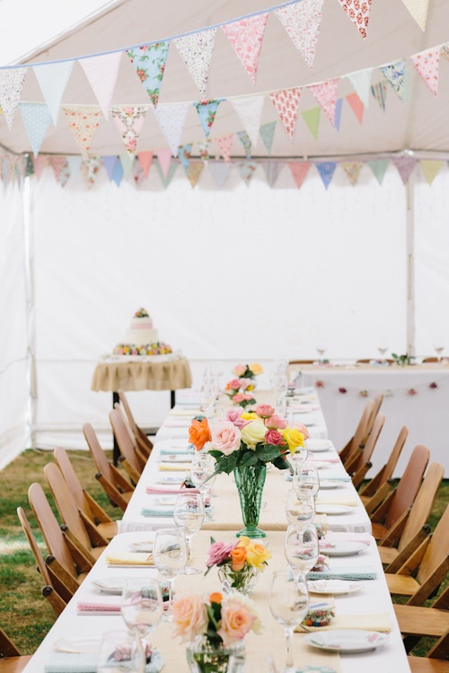 a bright summer wedding tablescape with colorful buntings, bright blooms and napkins and a neutral table runner for a bold summer wedding