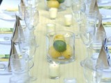 a bright summer wedding table with a printed yellow table runner, fruit centerpieces and candles and all neutral everything