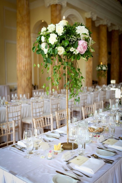 an elegant summer wedding tablescape with neutral place settings and linens and a white and pink tall floral centerpiece