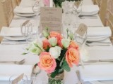a stylish neutral summer wedding tablescape with white linens, tags and bright orange blooms and greenery