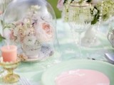a chic pastel wedding tablescape with light green and pink plates, linens, blooms and peachy candles plus pearl strands