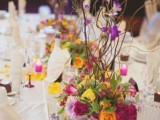 a bright summer wedding table with colorful florals and all white everything around plus candles