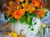 a bright fall or Thanksgiving wedding centerpiece of a white pumpkin, bold orange blooms and greenery is amazing