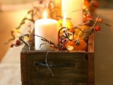 a wooden box with berries, pumpkins, gourds and candles is a stylish rustic centerpiece for a fall or Thanksgiving wedding