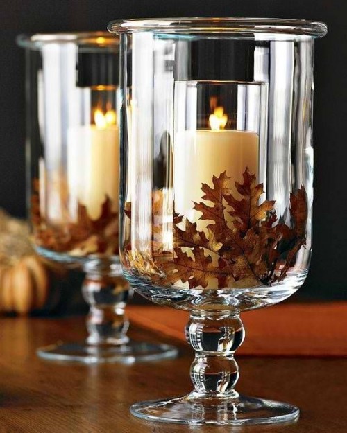 large glasses filled with fall leaves and with candles inside are gorgeous for rocking them at a fall wedding, this is a simple and lovely idea