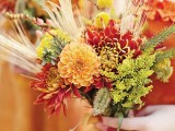 a bold fall wedding bouquet of burgundy, yellow and orange blooms, greenery and wheat is a lovely idea for the fall
