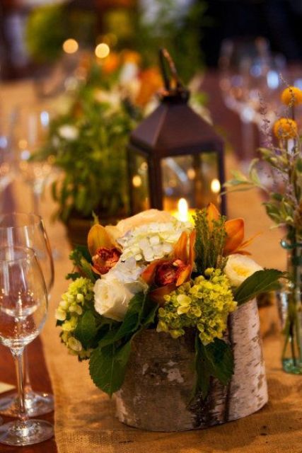 a fall or Thanksgiving wedding centerpiece of a tree stumps with neutral and bold blooms and greenery is chic
