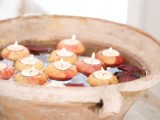 a concrete bowl with floating leaves and apples as candleholders is a lovely fall and Thanksgiving decoration to rock