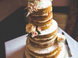 a naked wedding cake with frosting and jam, blush blooms, greenery and a bunting cake topper is a gorgeous idea for a summer wedding