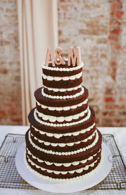a red velvet wedding cake with frosting and wooden monograms is a simple and cool idea for a summer or fall wedding