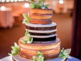 a naked wedding cake with usual and chocolate tiers, with lots of frosting and green flowers and candles around is a stylish idea for a summer wedding
