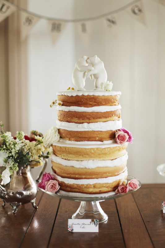 a naked wedding cake with lots of frosting and sugar cake toppers is a fantastic idea for a spring or summer wedding
