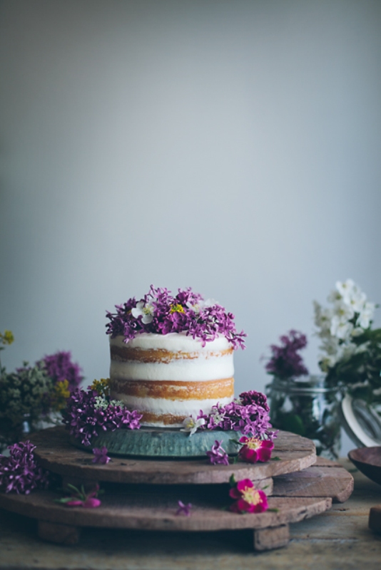 a naked wedding cake topped with lilac and white blooms is a lovely and delicate idea for a spring wedding