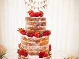 a naked wedding cake topped with strawberries and a tiered bunting wedding cake topper is a lovely idea for a summer wedding