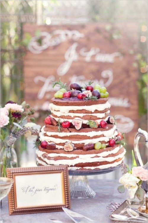a chocolate naked wedding cake with frosting, fresh berries, fruit and herbs is a fantastic idea for a summer or fall wedding with a touch of boho