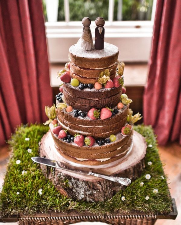 a naked wedding cake with frosting, fresh berries and greenery, kokeshi doll cake toppers is a gorgeous solution for a summer wedding