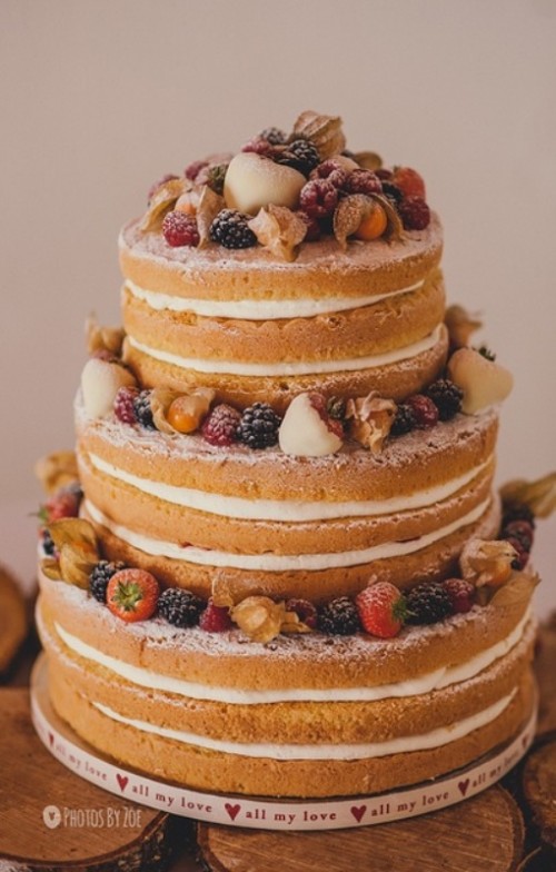 a fab and delicious naked wedding cake with fresh berries and fruit on top is a gorgeous idea for a refined summer wedding