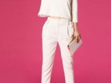 a retro-inspired bridal pantsuit with pants and a simple long sleeve top, white heels and a shiny glam clutch