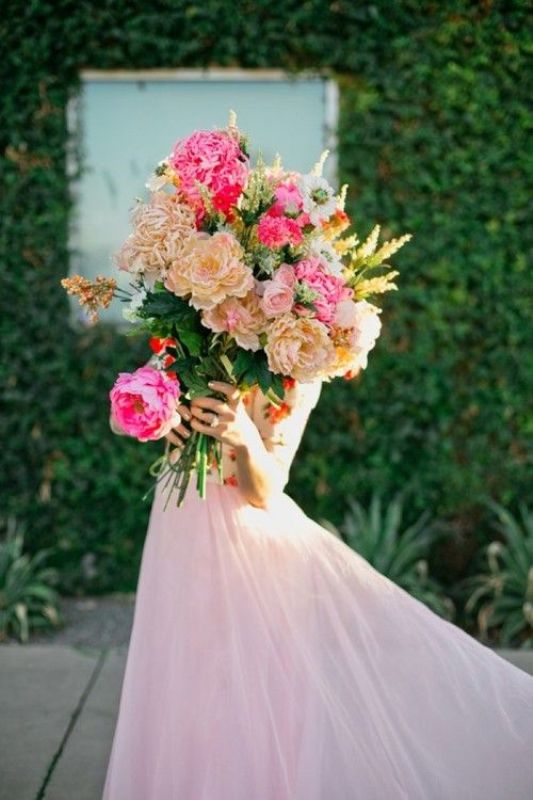 A large wedding bouquet of peonies, roses and garden roses in beige and hot pink is a lovely idea for a spring or summer bride