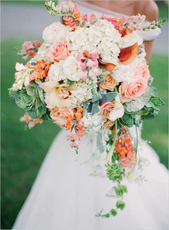 An oversized wedding bouquet with orange and white blooms, cascading greenery and a couple of cabbages is a fun idea for a summer farm wedding