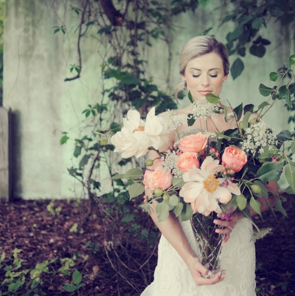 An oversized wedding bouquet compirsing white, peachy pink blooms, greenery and blooming branches as fillers