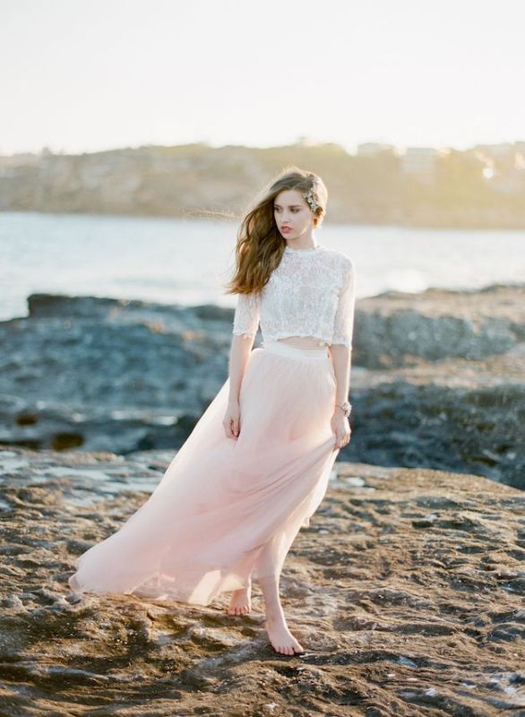 A white lace crop top with a high neckline and short sleeves, a pink flowy maxi skirt for a romantic and airy bridal look