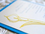 a blue wedding invitation with a yellow flower embroidered on it is a lovely and bold idea for a wedding with a crafty touch