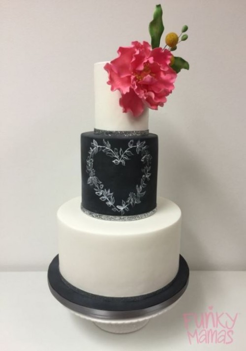 a black and white wedding cake with a black chalkboard tier, with chalking, with a bold bloom and leaves is a lovely idea for a modern wedding