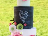 a bright black and white wedding cake with a chalkboard tier, with bright fresh and sugar blooms and greenery is amazing
