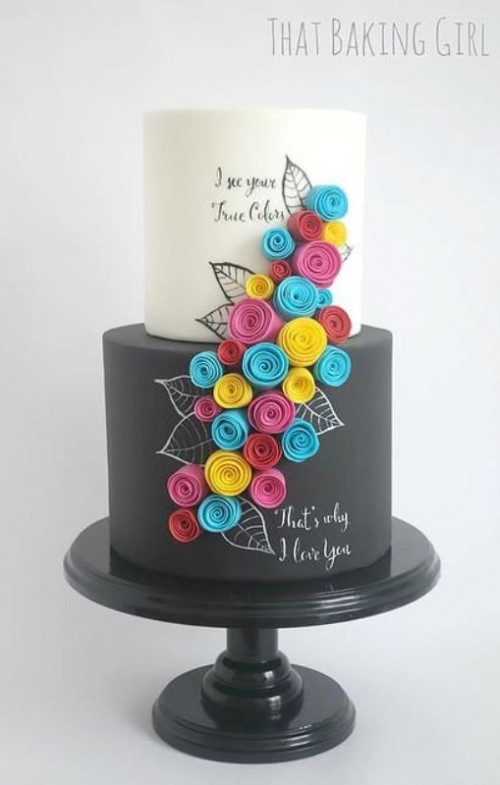 a black and white wedding cake with a chalkboard tier with chalking, with colorful fabric blooms and painting on the upper tier, too